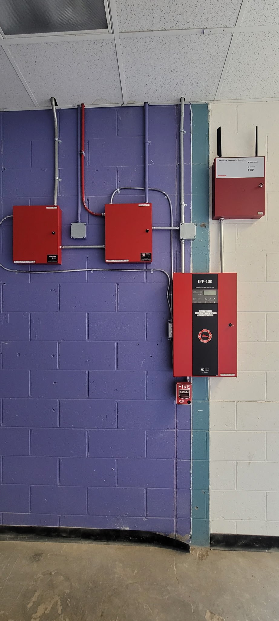 Multiple fire alarm control cabinets and conduit on commercial wall